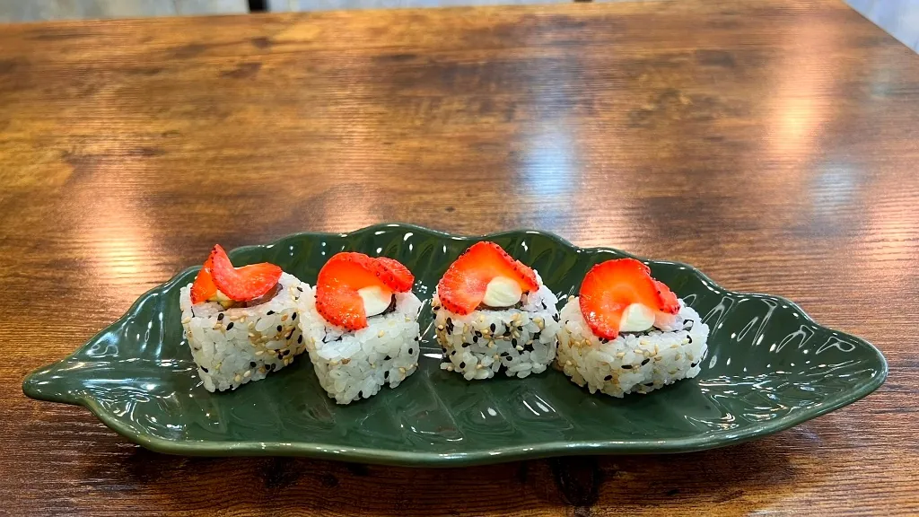 Uramaki con fresa servido sobre hoja verde